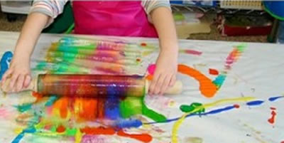 child painting with rolling pin